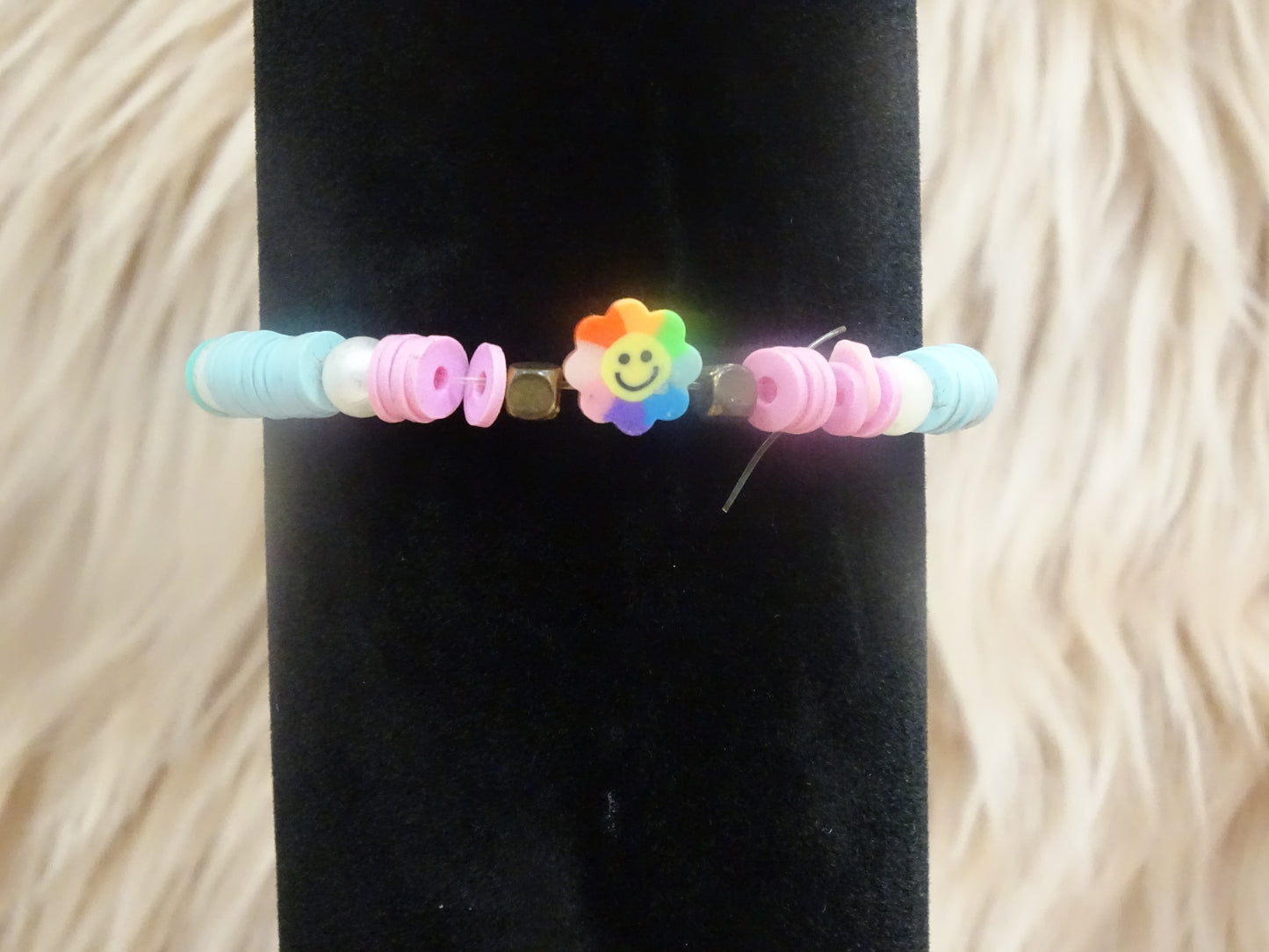 Regenboogkleurige armband met een vrolijk bloempje
