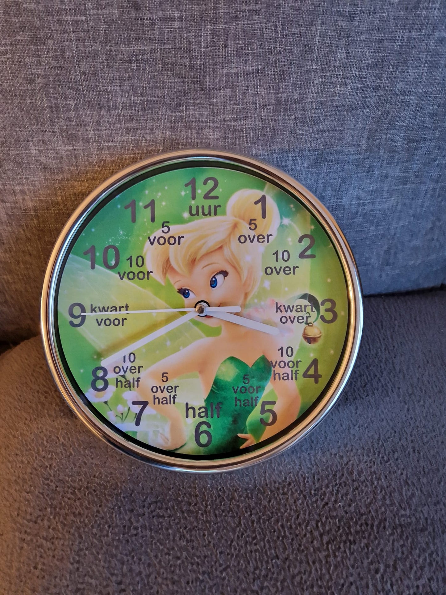 Kinderklok verkrijgbaar met een rand in wit, zandbeige, zwart of olijfgroen, met diverse themadesigns naar keuze. De klok heeft duidelijke cijfers en extra aanduidingen zoals "kwart voor" en "half" om kinderen te helpen bij het leren klokkijken. Een speelse en leerzame toevoeging aan elke kinderkamer!